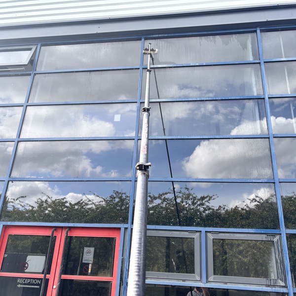 Cleaning the glazed shopfront above a reception entrance with a water fed pole